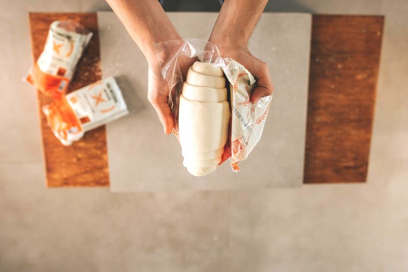 Mãos abrindo a embalagem de pão cru