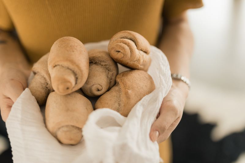 Mãos segurando mini pães sobre pano branco