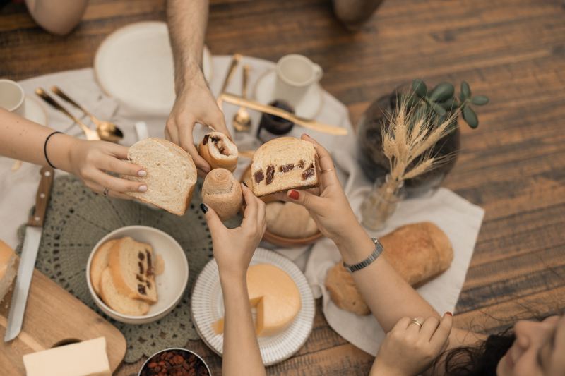 Mesa de café com mãos partindo pão recheado