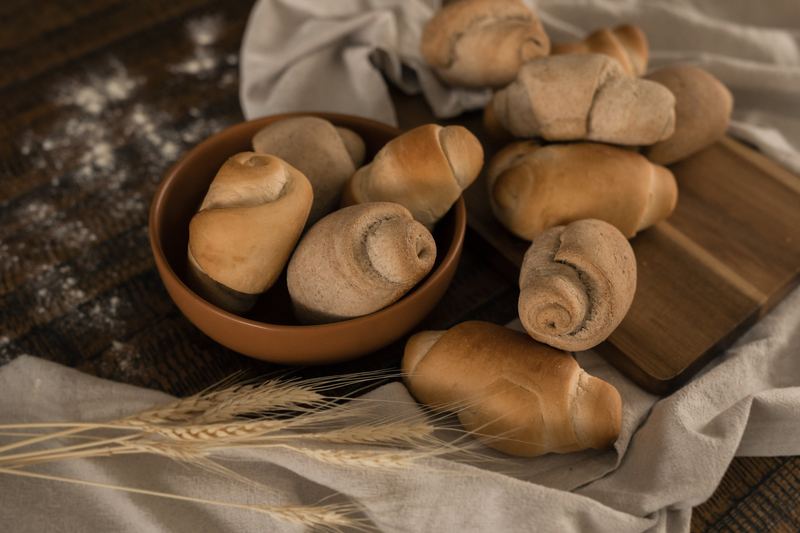 Mini pães em tigela de madeira com pano e trigo